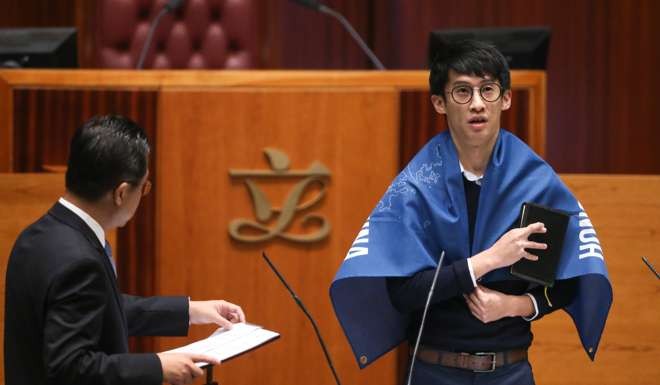 Under the ruling, Baggio Leung (draped in banner) and Yau Wai-ching would be barred from retaking their oaths. Photo: Sam Tsang