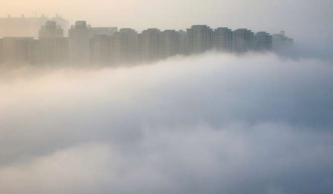 Residential buildings rise above thick fog in Yantai, Shandong province. Housing affordability is less of a concern in lower-tier cities. Photo: Reuters