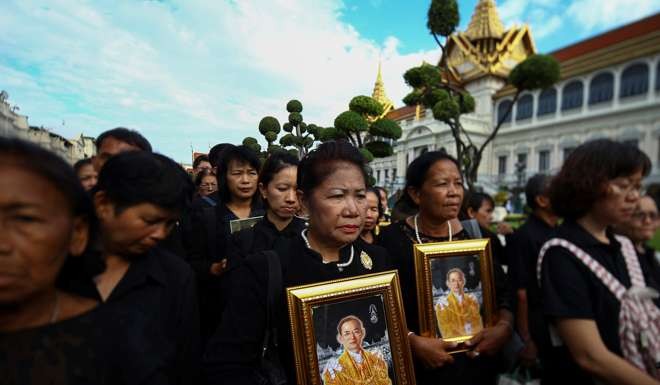 Mourners hold up pictures of Thailand’s late King Bhumibol Adulyadej as they walk to the throne hall at the Grand Palace in Bangkok to pay their last respects on November 2. Photo: Reuters