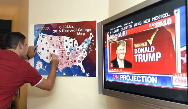 Jake Krupa colors in an electoral map as states projected for Republican presidential candidate Donald Trump or Democratic Presidential candidate Hillary Clinton at an election watching party in Florida. Photo: AFP