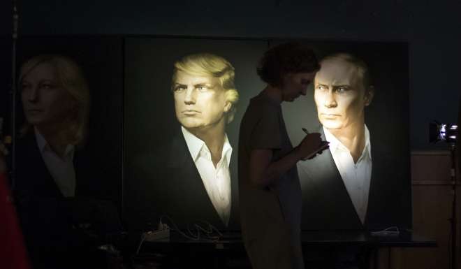 A journalist takes notes as she watches a live telecast of the US presidential election against the backdrop of portraits of Donald Trump and Russian President Vladimir Putin, at the Union Jack pub in Moscow on November 9. Russia's lower house of parliament has applauded Trump’s victory. Photo: AP