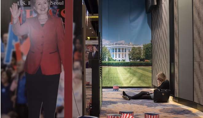 A woman sits on the floor behind a cut-out of Hillary Clinton at an election event organised by the US embassy, at a hotel in Seoul. Photo: AFP