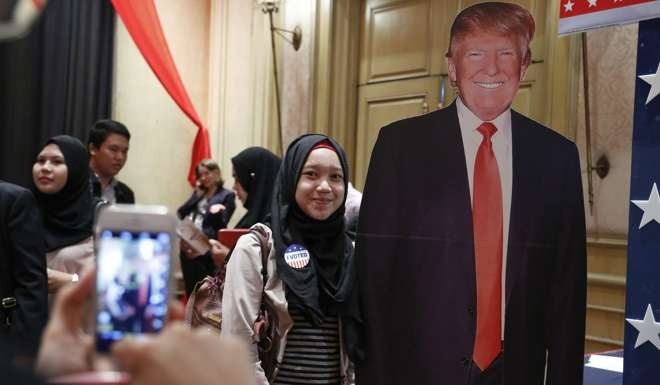 A Malaysian woman poses for a photograph next to a cardboard figure of Donald Trump during an event to watch the US presidential elections at a hotel in Kuala Lumpur, Malaysia. Photo: AP