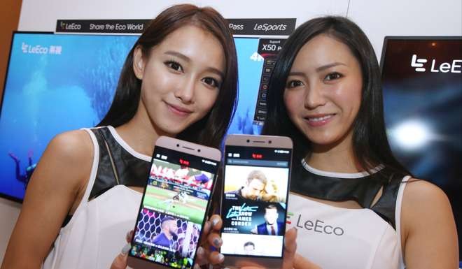 Two promoters show LeEco app on mobile during 