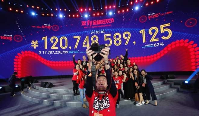 A staff member celebrates in front of the giant screen displaying total gross merchandise volume of Alibaba's online marketplace Tmall on November 11. Photo: Xinhua