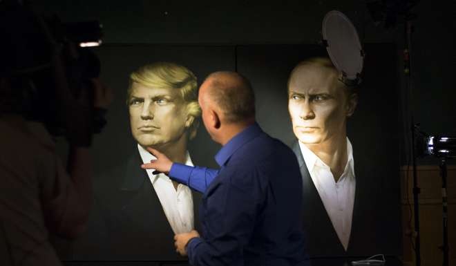A journalist points at a portrait of US President-elect Donald Trump, with a portrait of Russian President Vladimir Putin at right, during a live telecast of the US presidential election in the Union Jack pub in Moscow. Photo: AP