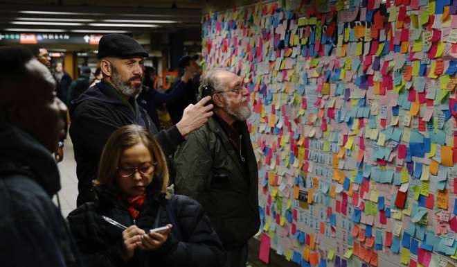 Commuters stop to read and photograph messages written on post-it notes regarding the election of President-elect Donald Trump in New York. Photo: Reuters