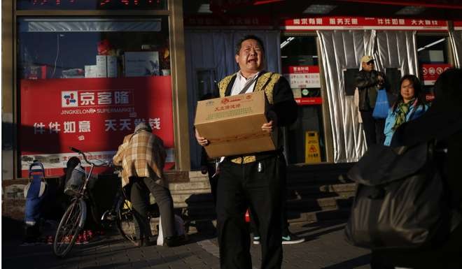 A Chinese man carries goods out of a supermarket in Beijing. China should abandon forced savings and give the money back to the household sector to develop a consumption-led economy. Photo: EPA