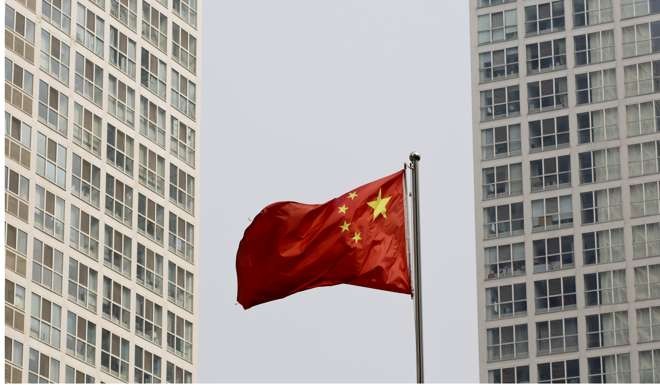 A Chinese national flag flutters in the wind in between a high-rise residential and office complex in Beijing, Photo: AP