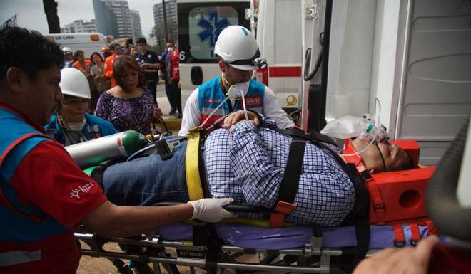 Peruvian rescuers help a victim of the fire at Larcomar mall. Photo: EPA