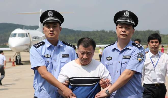 Policemen escort repatriated Yang Jinjun in Fuzhou, Fujian Province, as part of operation Skynet. Photo: Xinhua