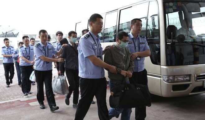 Six fugitives accused of economic crimes are taken back into Chinese custody after being repatriated from Indonesia at Capital International Airport in Beijing. Photo: Xinhua