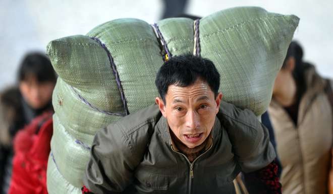 A passenger carries his luggage to board a train at Changsha Railway Station in Changsha, Hunan Province. The first generation of migrant workers helped forge China’s economic miracle. Photo: Xinhua