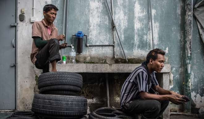 Workers rest after cutting old tyres, which will be recycled, in an alley in Ampang, in the suburbs of Kuala Lumpur. Malaysian PM Najib Razak has secured deals with China worth deals worth RM144 billion to the Malaysian economy. Photo: AFP