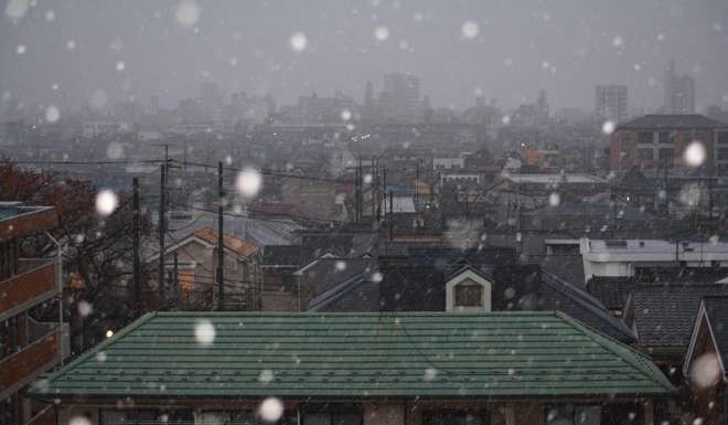 Snow falls across the rooftops of residential buildings during the early morning hours in Tokyo. Photo: AFP