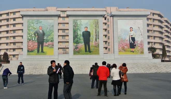 A group of Chinese look at murals of former North Korea leaders Kim Il-sung, left, and Kim Jong-Il in the North Korean border town of Siniuju, across from China’s Dandong. Photo: AFP