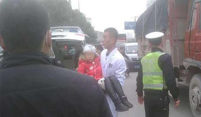 A medical staff carries an injured girl on the street in Hanzhong, Shaanxi province. Photo: SCMP Pictures
