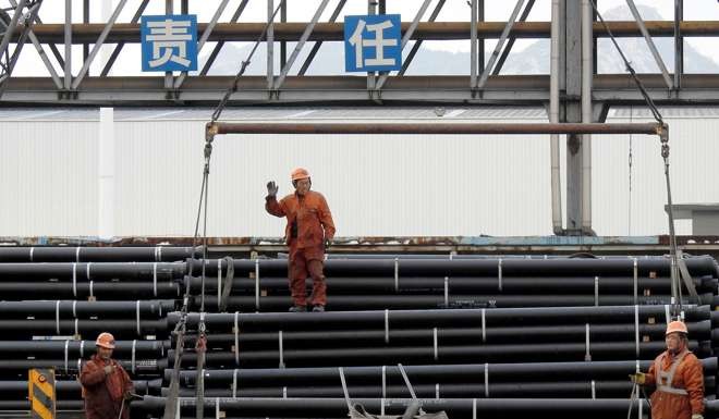 Chinese workers load steel tubes on to a truck at a logistics centre in Jiangsu province. Photo: AFP