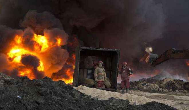 Firefighters work to well an oil fire set by Islamic State militants south of Mosul. Photo: AP