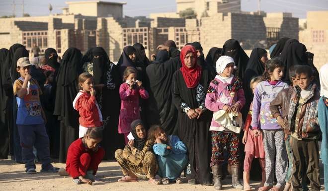 Civilians wait for humanitarian aid to be distributed outside Mosul. Photo: AP