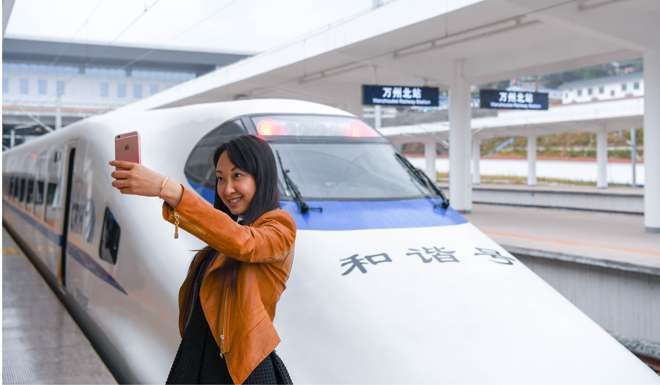 A woman takes a selfie in front of a train at a station in Chongqing. The Wanzhou-Chongqing section of the Zhengzhou-Chongqing high-speed railway line will go into operation this year. Photo: Xinhua