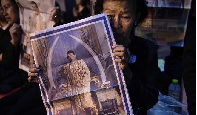 A woman holds a newspaper image of Thai Crown Prince Maha Vajiralongkorn outside of the Grand Palace in Bangkok. Photo: AFP