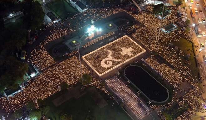 Thai people light candles showing Thai script numbers representing the late Thai King Bhumibol Adulyadej (L) and the future king at a park in Bangkok on Wednesday. Photo: AFP