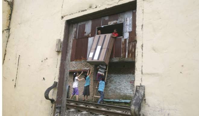 Residents lower a cabinet from the second floor of a house, after an eviction last month at a slum in Medan, North Sumatra, Indonesia. Dozens of buildings were demolished by the local authorities to clear the area for the construction of a new railway track. Where relocation is inevitable, municipal officials must always ensure that the new homes provided offer as much comfort as the ones vacated. Photo: AP