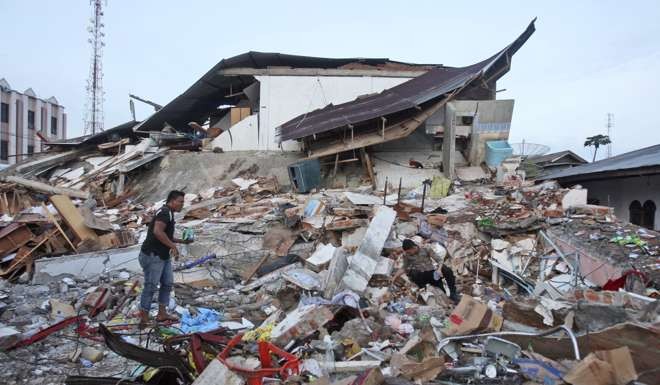 An Acehnese man and a police officer survey the damage after an earthquake in Ulhee Glee. Photo: AP