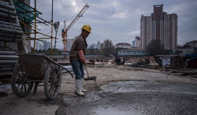 A man fills a wheel cart with cement at a construction site of a residential skyscraper in Shanghai. Photo: AFP