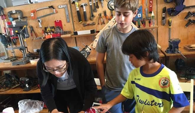 Instructor Monica Leung guides students Henrique Bastos (left) and Emilio Migliorelli (right) during a Makerbay workshop.