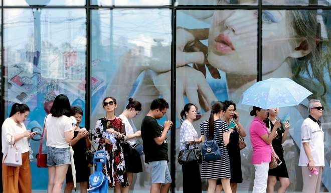 Shopping wait in line to go into a shop in Shanghai. Photo: Reuters