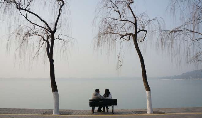 People sit on a bench at a park in Beijing during heavy smog on Sunday. Photo: Reuters
