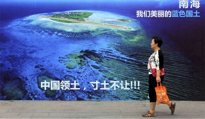 A woman walks past a billboard in Weifang, Shandong province, highlighting the South China Sea dispute. There’s a strong belief in China that the US is working to contain China internationally, while in the US, there are clear concerns in some quarters that China may become an assertive hegemon in Asia. Photo: Chinatopix via AP