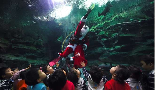 Children watch a diver wearing a Santa Claus suit swim with fish in a tank during a Christmas event at the Lotte World Aquarium in Seoul. The people of Hong Kong, Singapore, South Korea and Taiwan should relax, be happy and, above all, make more babies. Photo: AFP