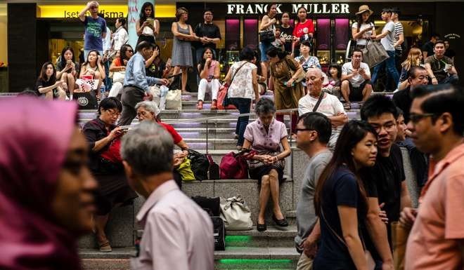 People sit on steps on Orchard Road in Singapore. All four tiger economies have invested massively in the development of human resources. Photo: Bloomberg