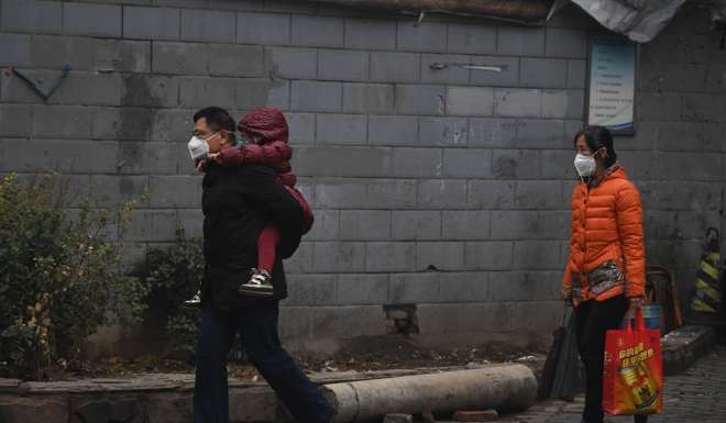 A father carries his child on a heavily polluted day in Shijiazhuang in Hebei province. Photo: AFP