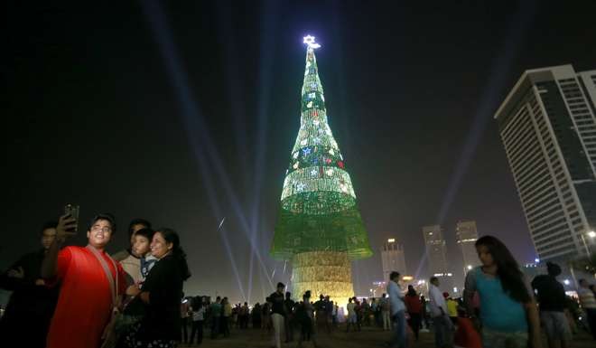 A Sri Lankan family takes photographs standing near the enormous artificial Christmas tree. Photo: AP