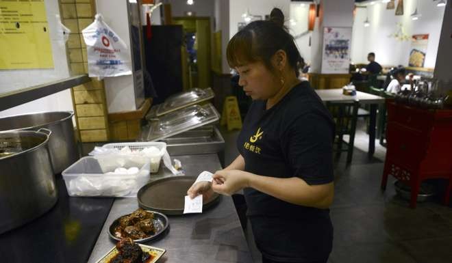 A waitress preparing a plate of rabbit's head for customers at a restaurant in Sichuan’s capital. Photo: AFP