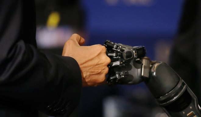 US President Barack Obama bumps fists with a robotic arm operated by Nathan Copeland, a quadriplegic brain implant patient who can experience the sensation of touch and control the remote robotic arm with his brain. Obama was touring innovation projects at the White House Frontiers conference in Pittsburgh on October 13. Photo: Reuters
