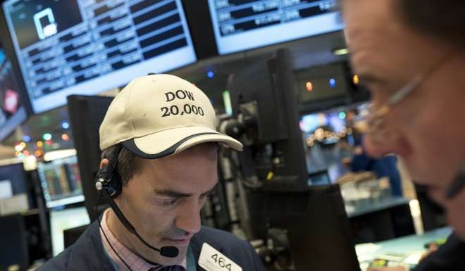 Gregory Rowe follows stock prices at the New York Stock Exchange while wearing a Dow 20,000 cap. Photo: AP