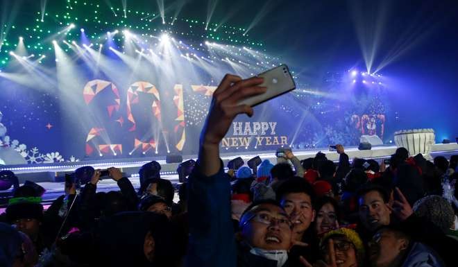 People pose for pictures as they attend a New Year's Eve countdown event in Beijing. Photo: Reuters