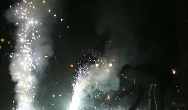 An Indian man lights firecrackers on the street during the New Year celebration in Mumbai. Photo: AP