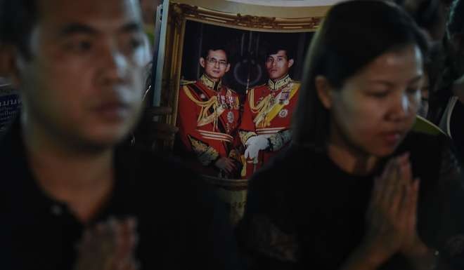 People hold images of Thai King Maha Vajiralongkorn with his late father, King Bhumibol Adulyadej, during New Years celebrations. Photo: AFP
