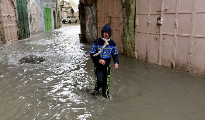 A Palestinian boy walks through a flooded street in the Old City or “Casbah” of Hebron, in the West Bank on December 14. Extreme weather blamed on climate change has been affecting many places on the Eastern Mediterranean, bringing snow and flooding. Photo: EPA