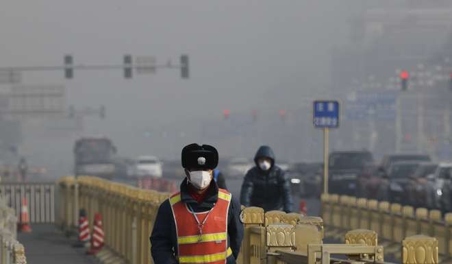 A traffic warden wearing a protection mask walks on a street near Tiananmen Square in Beijing. Photo: AP