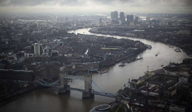 Tower Bridge, centre, and the Canary Wharf business district can be seen in the distance as the River Thames flows through London. Photo: AP