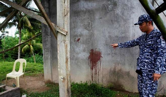 A prison officer points to a wall with blood stains where a prison guard who was killed. Photo: Reuters