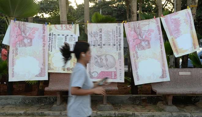 A jogger passes replica prints of the demonetised 500 and 1000 rupee notes as part of a street art exhibition in Mumbai. Photo: AFP