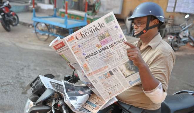 An Indian man reads a newspaper covering the withdrawal from circulation of the 500 and 1,000 rupee notes. Photo: AFP
